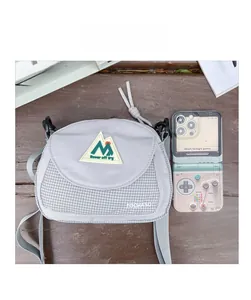 Close-up of a grey nylon crossbody bag shown next to a smartphone for size reference