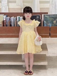 Détail de robe jaune en coton avec broderie florale et col à volants sur enfant