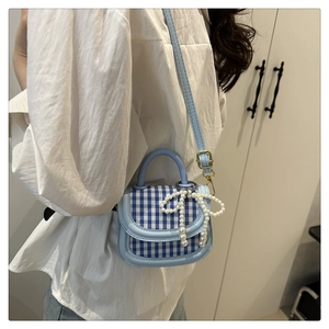 Detailed view of a sweet blue plaid mini handbag with elegant pearl bow decoration