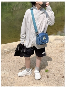 Detailed view of child wearing a blue outdoor crossbody bag by the lakeside