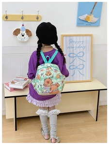 Detail of light green checkered backpack featuring cute bear and cake prints for kids