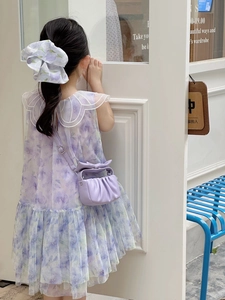 Detail of floral purple dress and matching bow bag on a girl in a soft lighting