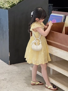 Détail d'un sac à main croissant en dentelle crème avec une robe jaune fleurie enfant