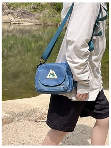 Detail of blue nylon crossbody bag with textured grid and outdoor triangle logo