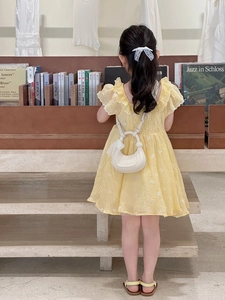 Détail d'un mini sac demi-lune blanc avec bordure en dentelle sur robe jaune
