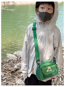 Close-up of bright green nylon crossbody bag for kids featuring a mountain peak logo