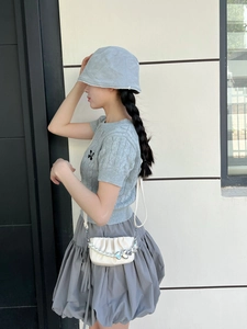 Détail du sac à main plissé blanc avec bandoulière perle et cœur argenté sur modèle