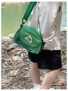 Detail of green nylon crossbody bag with mesh panel and adjustable strap in outdoor use