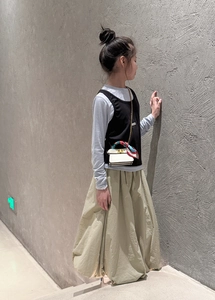 Close-up of a mini white chain bag with a decorative floral silk scarf on a child model