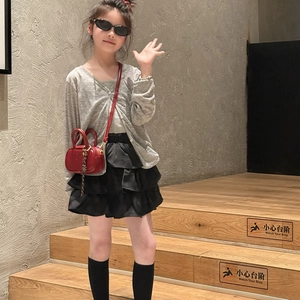 Fillette en cardigan gris et jupe noire avec un mini sac à bandoulière rouge tendance