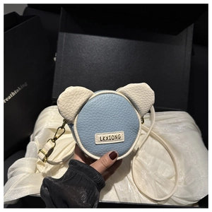 Dettaglio della borsa a tracolla bicolore a forma di orso con texture in pelle e logo