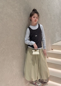 Fashionable girls' layered autumn outfit with a blue top, black vest, and khaki skirt