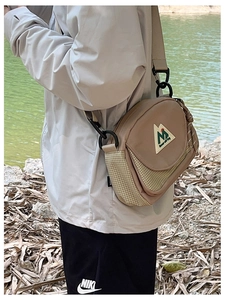 Detail of khaki outdoor crossbody bag with grid pattern and carabiner on model
