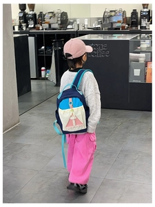 Detailed view of the color-block kids backpack with navy blue fabric and pink buckles