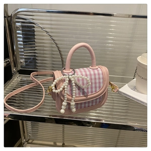 Detail of pink plaid mini handbag featuring a large pearl bow and elegant fabric texture