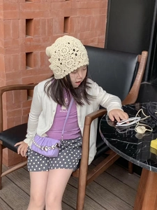 Détail d'un enfant portant un bonnet en crochet beige avec des motifs floraux évidés