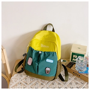 Detail of yellow and green color-block backpack with decorative patches on lace table