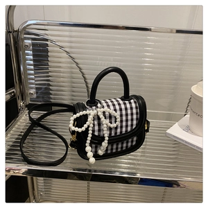 Close-up of black and white checkered mini bag with pearl bow and gold hardware detail