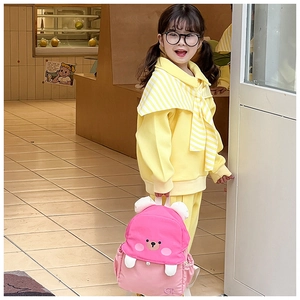 Detailed view of cute pink teddy bear backpack with 3D ears on a young girl model