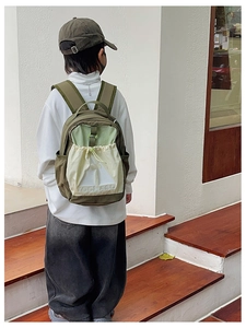 Outdoor view of kids olive green backpack with cream pocket and TOCHASO logo lettering