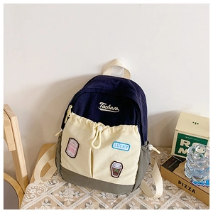 Detail of color-block canvas backpack with drawstring pocket and embroidery patches