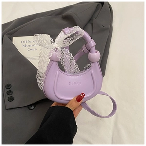 Détail du sac croissant lavande avec nœud en dentelle blanche et gaufrage de la marque