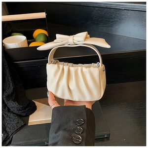 Detail of a beige mini cloud handbag with a large bow handle and pleated leather texture