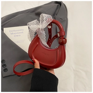 Détail du sac croissant rouge avec poignée à perles et nœud en dentelle blanche