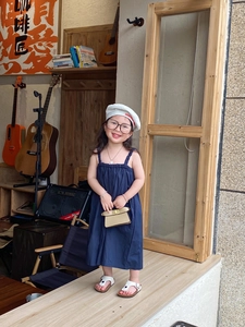 Detailed view of child fashion model wearing navy dress with white beret and accessories