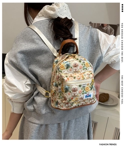 Close-up of cute cartoon bear and floral embroidery on a white canvas mini backpack