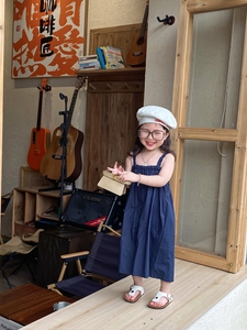 Girl in dark blue dress with cream handbag and stylish pearl necklace in retro studio