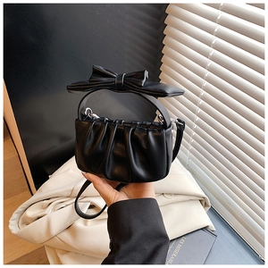 Detail of black pleated cloud bag for girls with large bow handle and leather strap