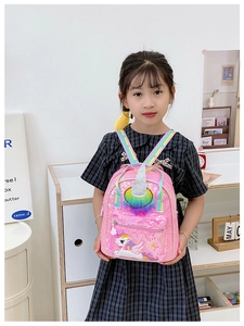 Close-up of pink sequin unicorn backpack with rainbow straps worn by a little girl