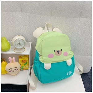 Detail of cute cartoon bear pattern on green and blue kids backpack with fabric straps