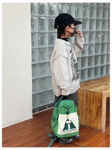 Outdoor shot of a high-capacity green children's backpack with cream contrast pockets