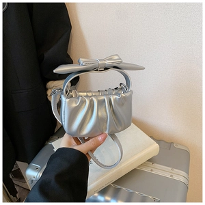 Detail of silver metallic girl's mini handbag with pleats and large bow handle