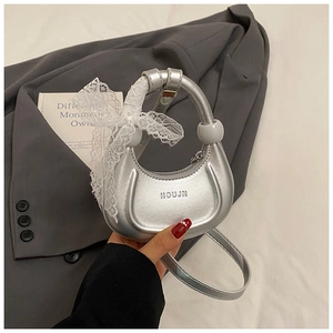 Détail du sac croissant argenté avec nœud en dentelle et finition métallique marque HOUJN