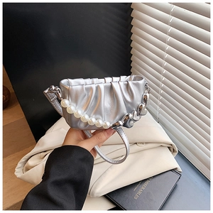 Détail du sac nuage argenté métallisé avec chaîne cœur en perles et tenue à la main chic