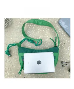Sac à bandoulière vert en maille pour enfants comparé à un iPad pour illustrer la taille