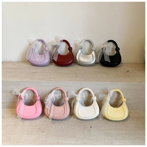 Détail de mini sacs demi-lune colorés avec nœuds en dentelle sur socle en pierre