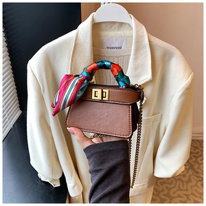 Close-up of brown litchi pattern mini handbag with gold chain and silk scarf