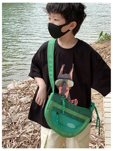 Détail du sac bandoulière enfant en nylon vert fluo avec mesh porté par un garçon
