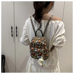 Detail of mini cartoon backpack featuring dense character prints and plush moon charm