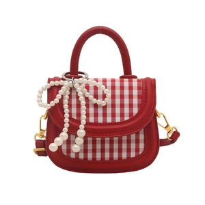 Mini red leather handbag with pearl bow and red plaid flap detail on white background