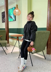 Dettaglio di una mini borsa marrone con ciondolo a cucciolo su una ragazza in abiti sportivi