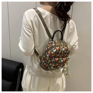Detail of cute cartoon printed mini backpack with gold zipper and pompom accessory