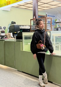 Dettaglio di una giacca nera con cappuccio per bambini e mini borsa a tracolla cucciolo