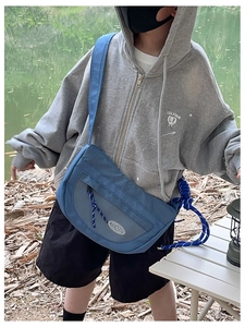 Sac à bandoulière bleu pour garçon porté par un mannequin dans un décor de camping