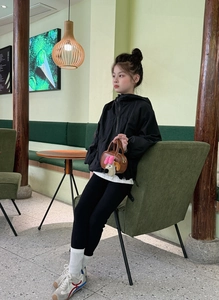 Ragazza con giacca nera e mini borsa marrone con un simpatico ciondolo a cucciolo