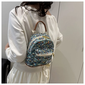 Detailed side view of mini fashion backpack with ocean print and brown handle worn by model